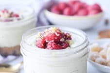 Matcha cheesecake parfait in a glass mason jar topped with berries.