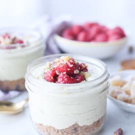 Matcha cheesecake parfait in a glass mason jar topped with berries.