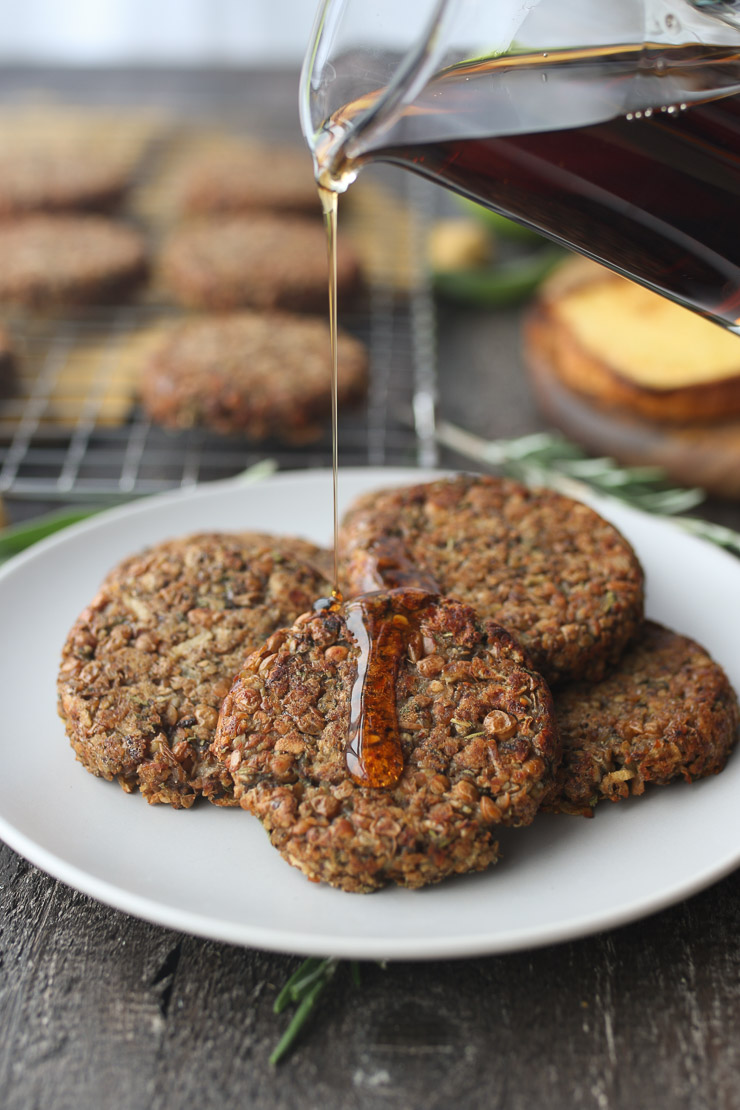 Maple syrup pouring over vegan breakfast sausage patties on a plate.