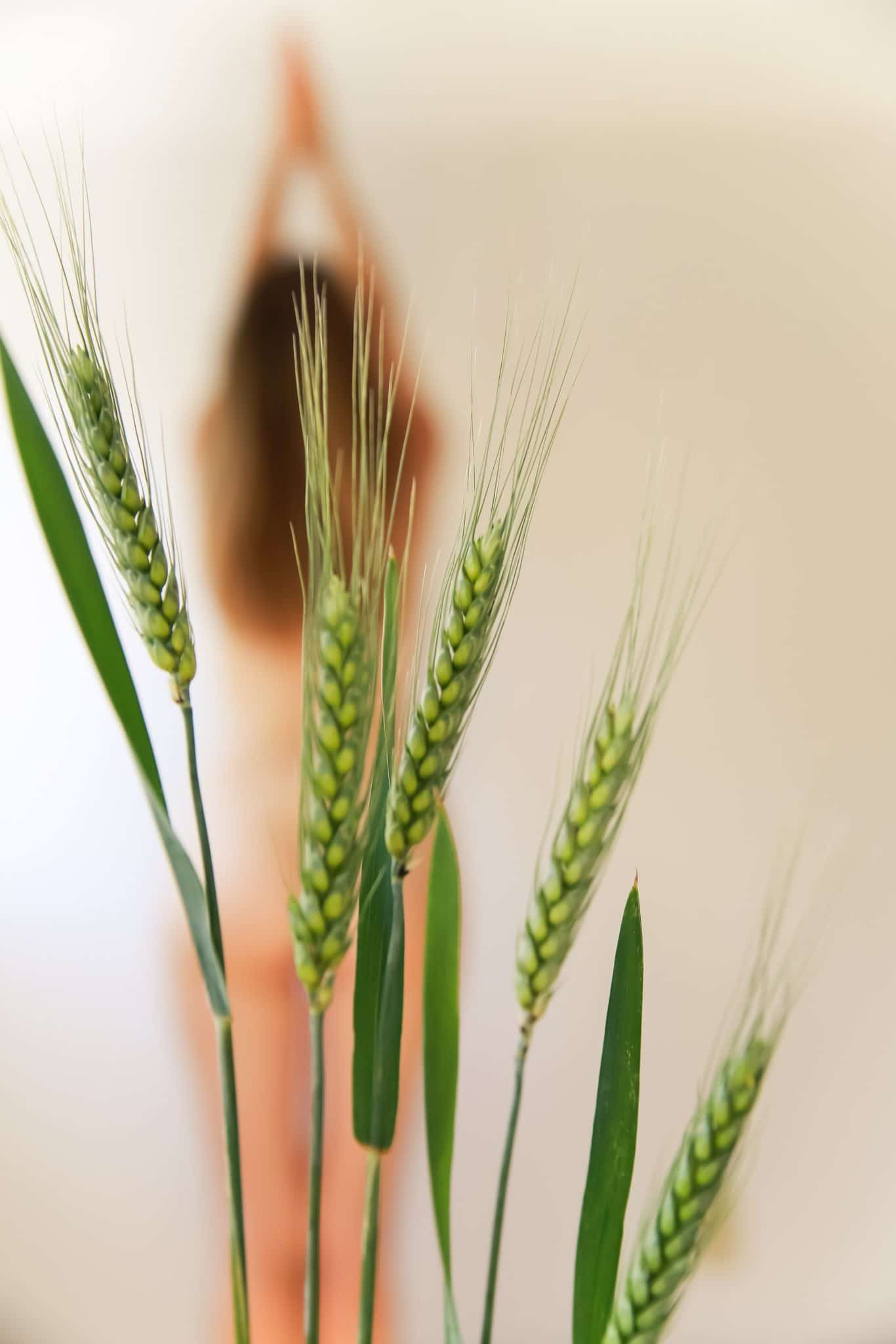 Blurred woman standing in background with green leaves in foreground. 