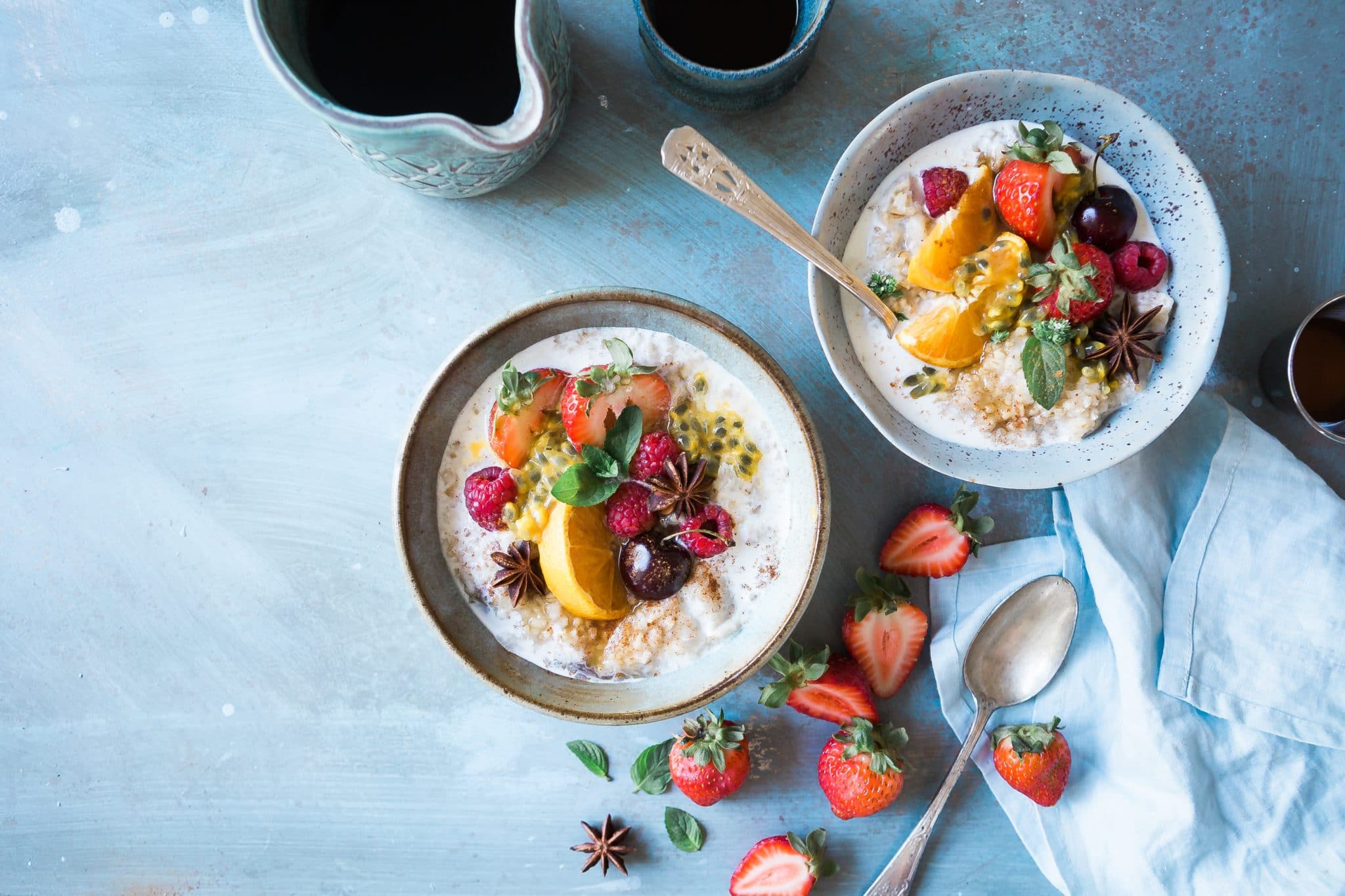 Two bowls of yogurt topped with a variety of fruit. 