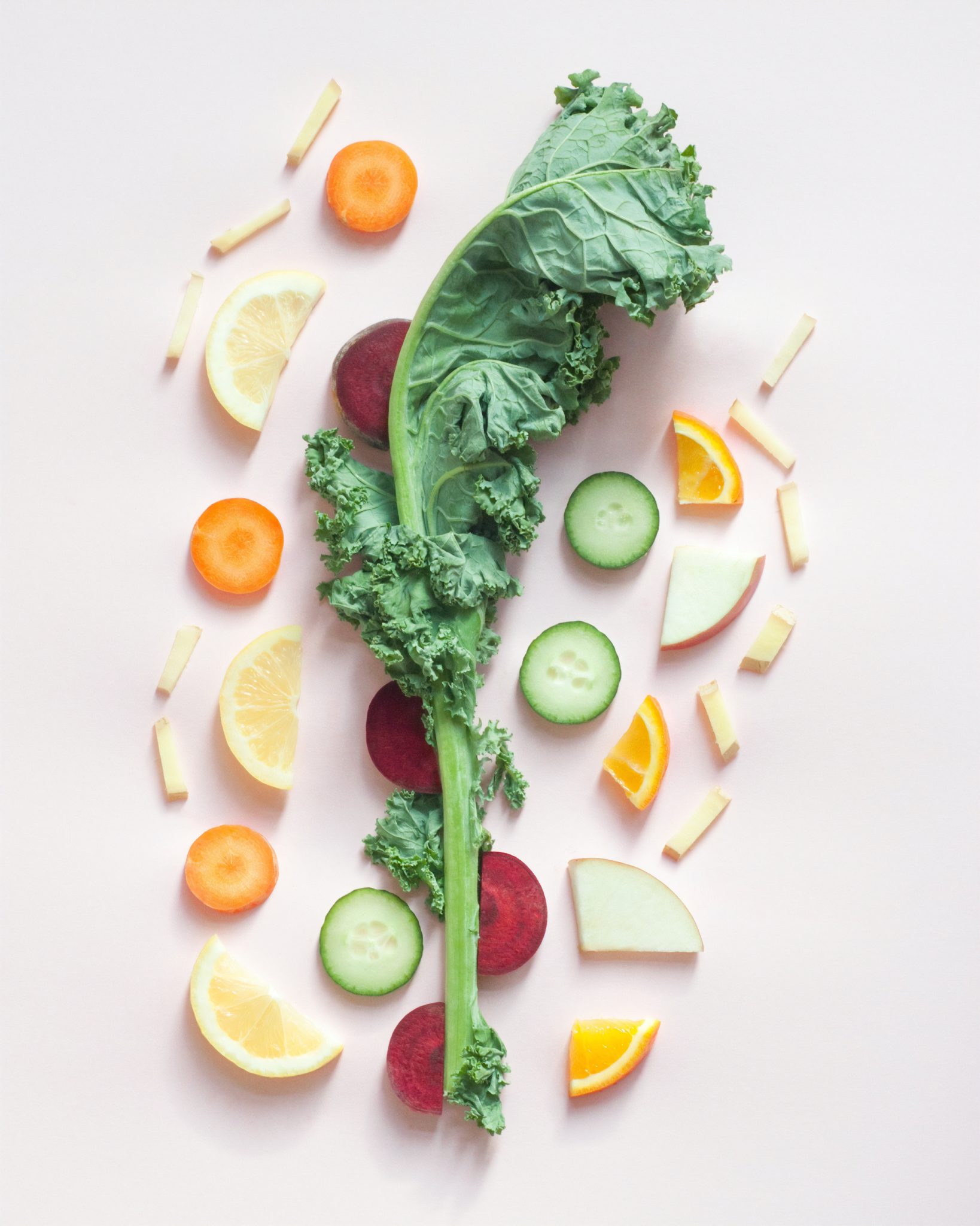 A kale stem on top of chopped fruits and vegetables representing the pegan diet