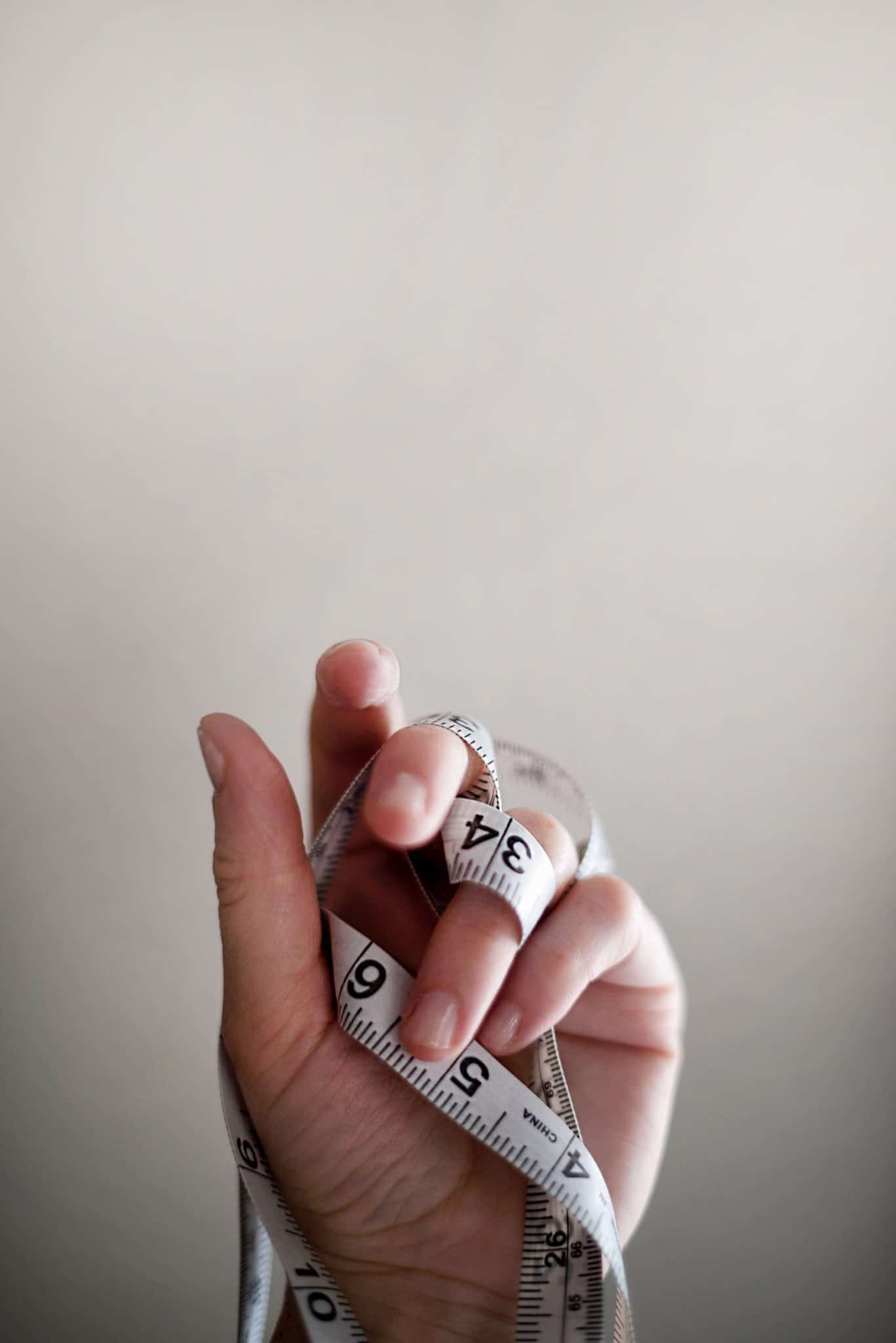 A hand with a tape measure wrapped around fingers