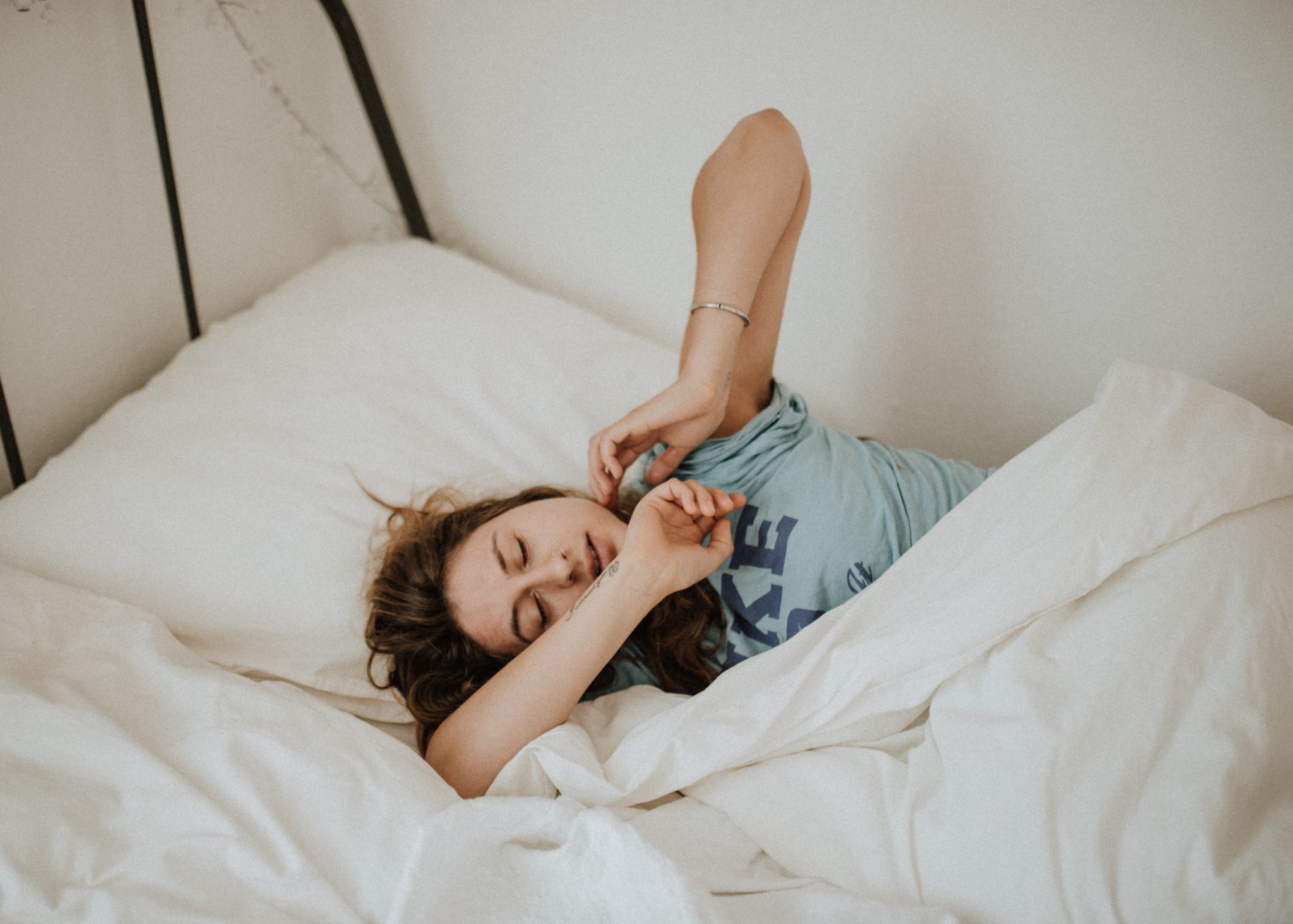 Woman with PCOS sleeping in her bed with white sheets. 