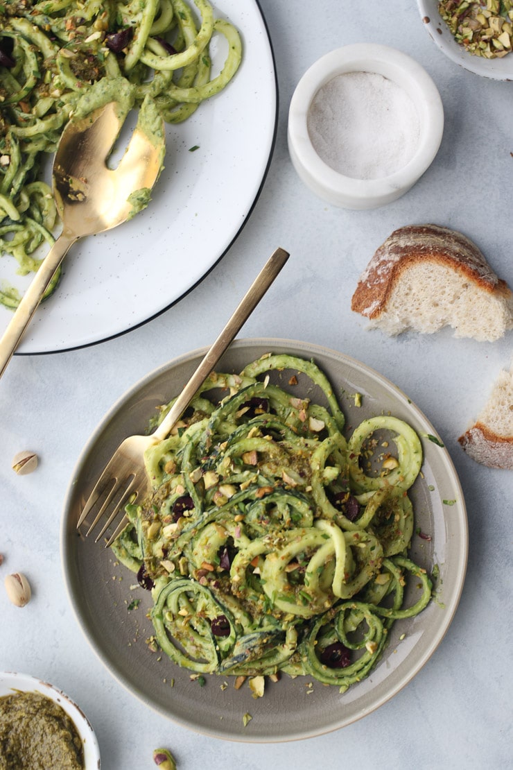Green avocado zucchini noodles with pesto on a grey plate.