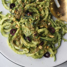 Zucchini noodles in creamy green sauce on a white plate.