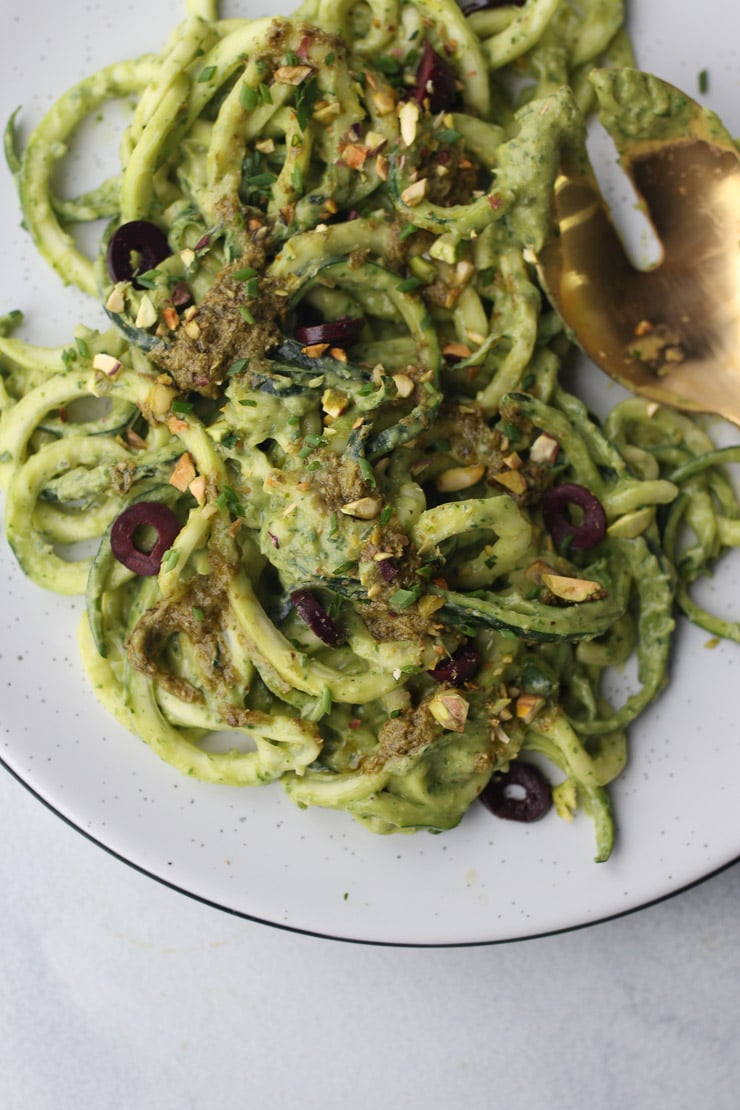 Zucchini noodles in creamy green sauce on a white plate.