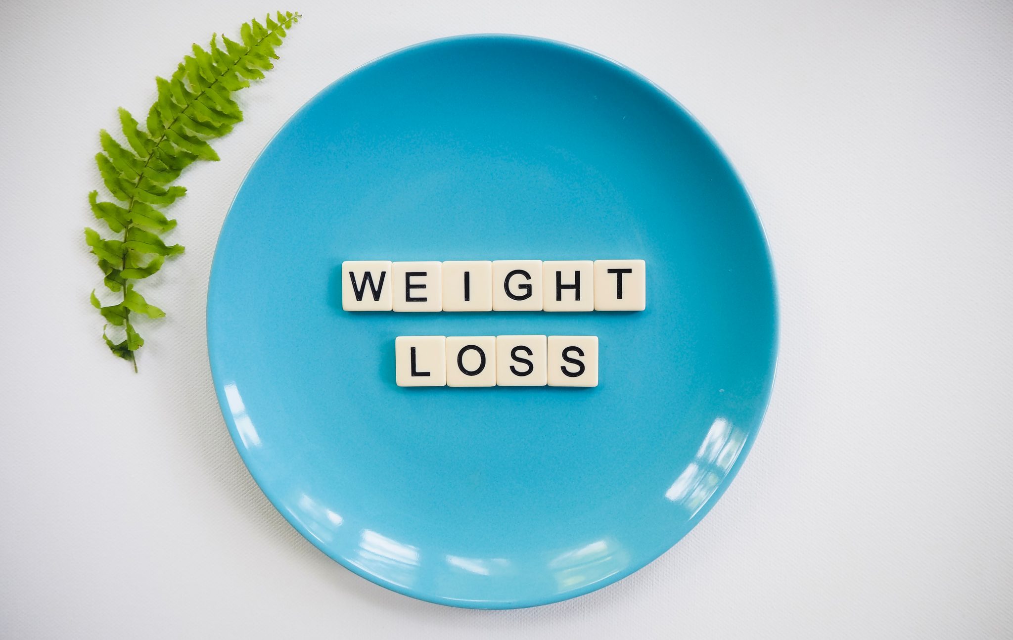 Blue plate with tiles that spell "weight loss" against a white background.