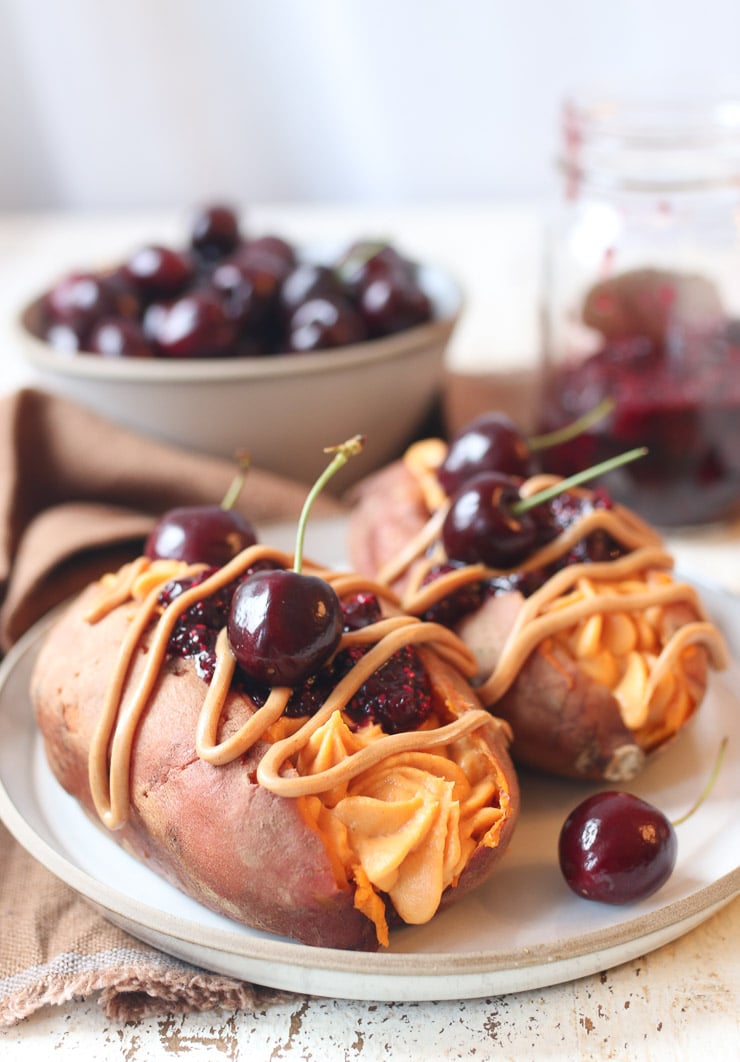 two stuffed sweet potatoes on a plate with PB&J on top. 