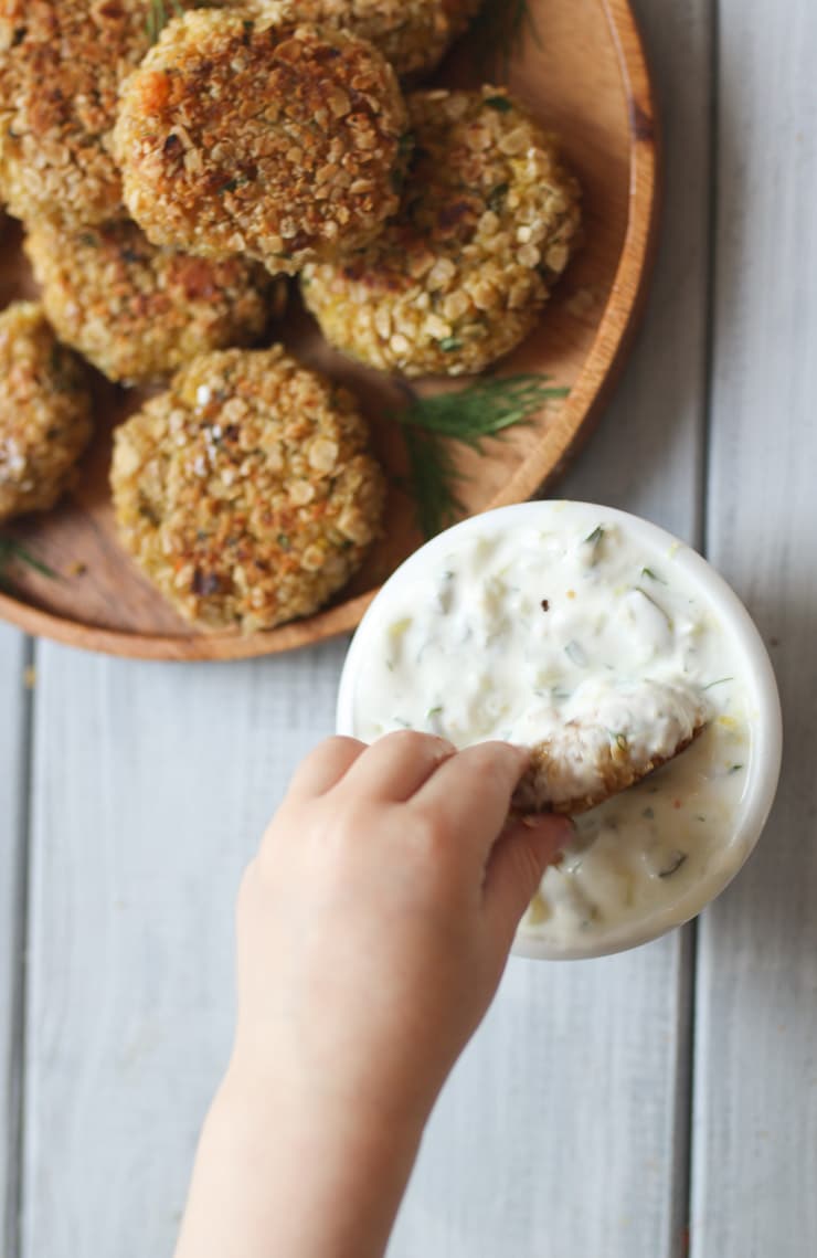 Toddler dipping fish cake into dip. 