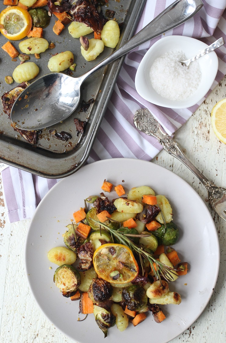 birds eye view of Gnocchi and vegetables on a plate next to a sheet pan with additional food