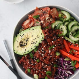 Big bowl containing avocado, veggies and vegan meat.