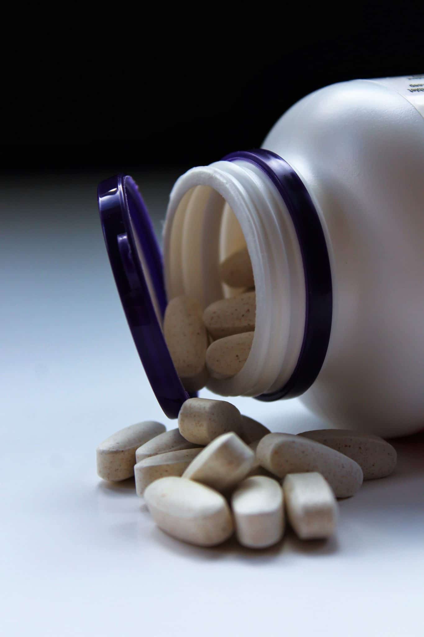 Bottle of supplements with capsules pouring out 