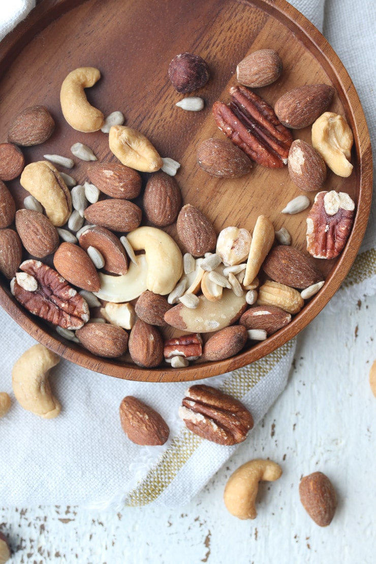 Mixed nuts on a wooden plate as part of a heart healthy diet.