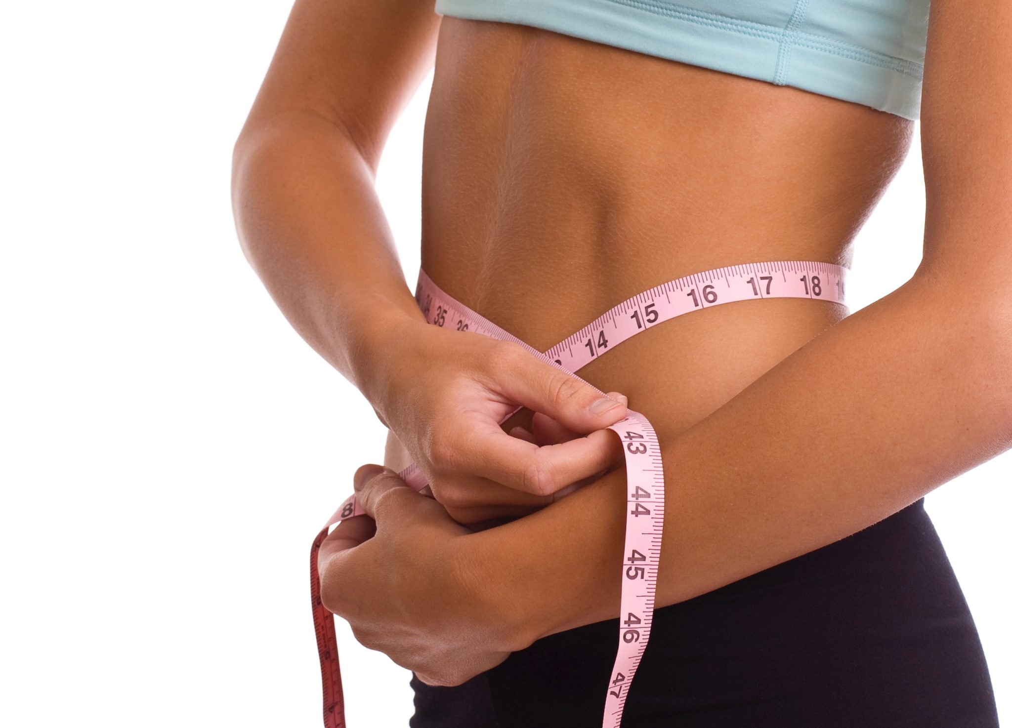 Female body builder using a tape measurer to measure her waist.