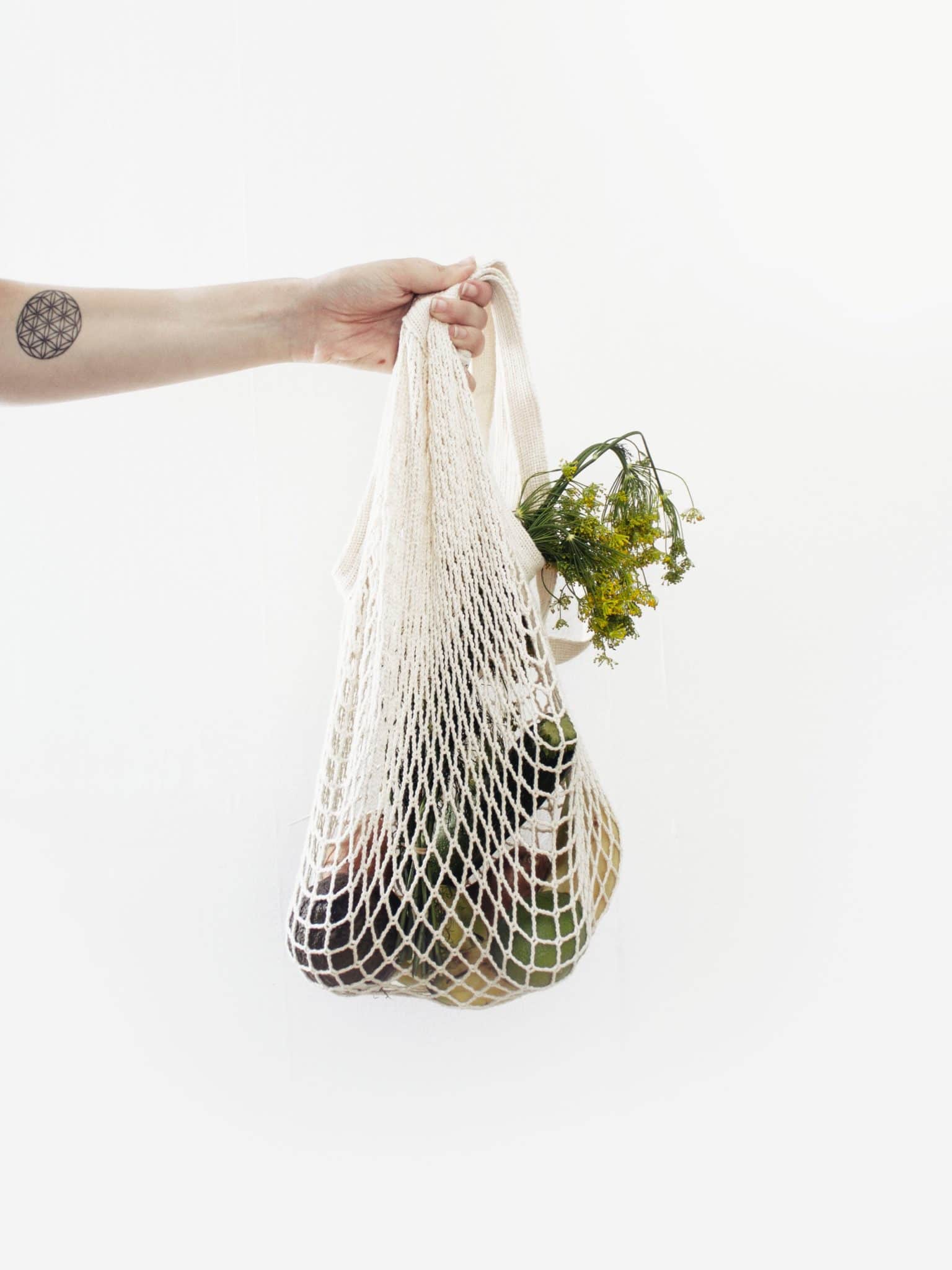 person carrying a reusable grocery bag with produce 