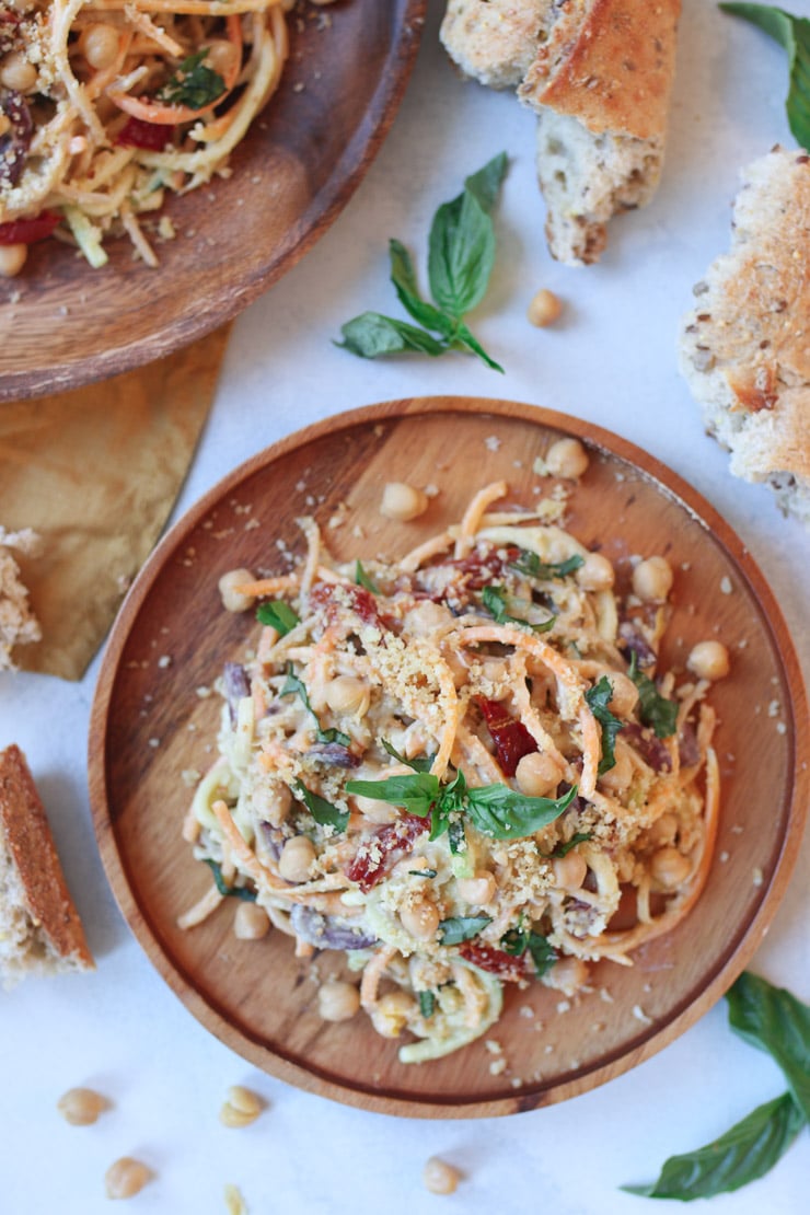 Birds eye view of vegan hummus pasta sauce with zucchini noodles on a wooden plate.