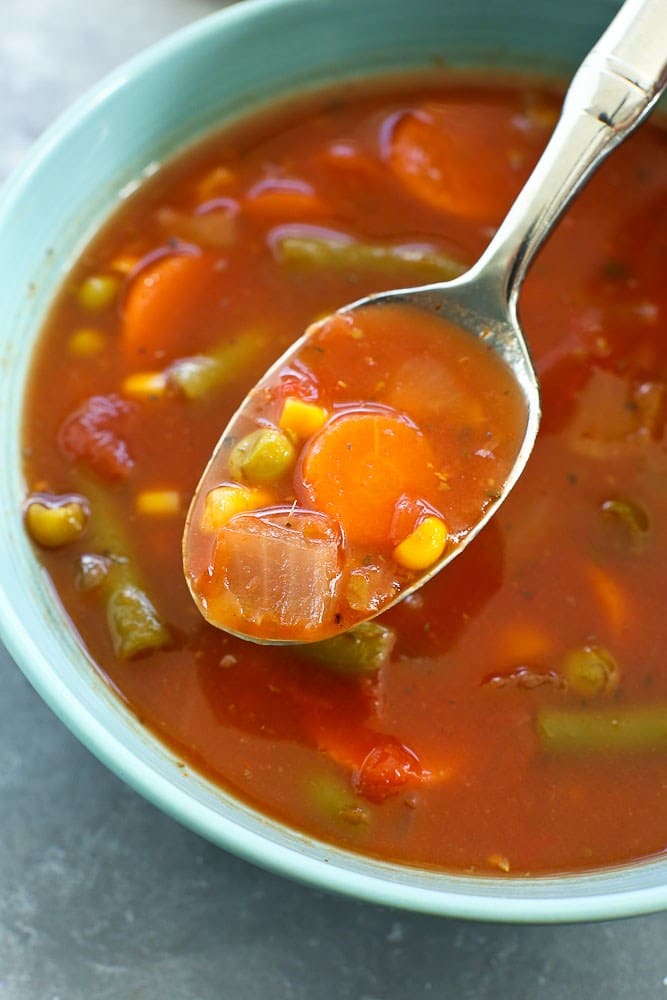 close up of a spoon taking a spoonful of pantry staple friendly 15 minute vegetable soup with canned and frozen vegetables 