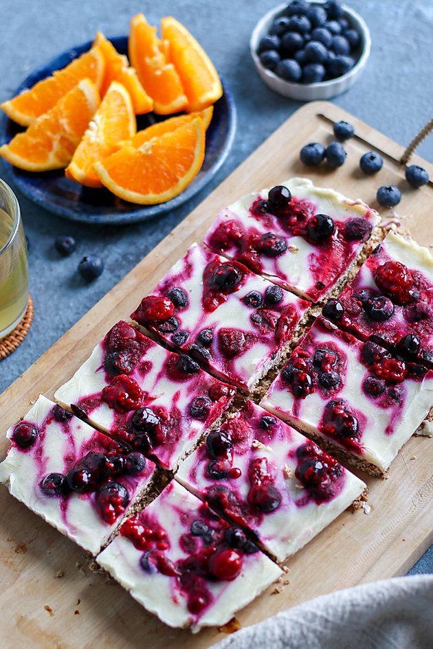 birds eye view of pantry staples frozen yogurt breakfast bars garnished with berries served on a wooden surface next to fresh orange slices