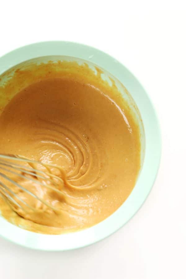 birds eye view of give ingredient peanut sauce recipe for social isolation in a blue bowl being swirled by a whisk 