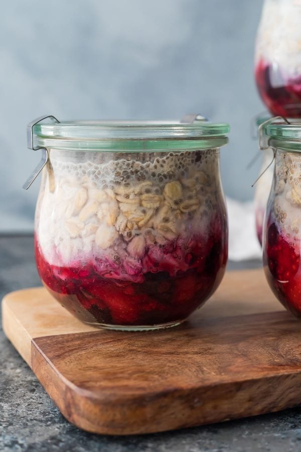 close up of pantry staple fruit on the bottom overnight oats in a clear jar on a wooden counter