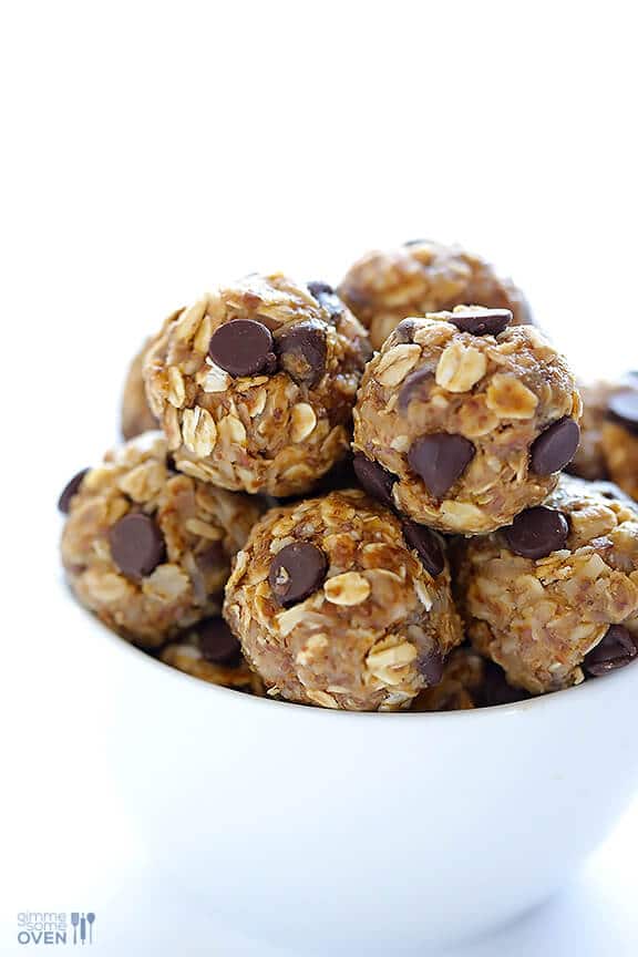 close up of multiple no bake energy bites garnished with chocolate chips in a white bowl