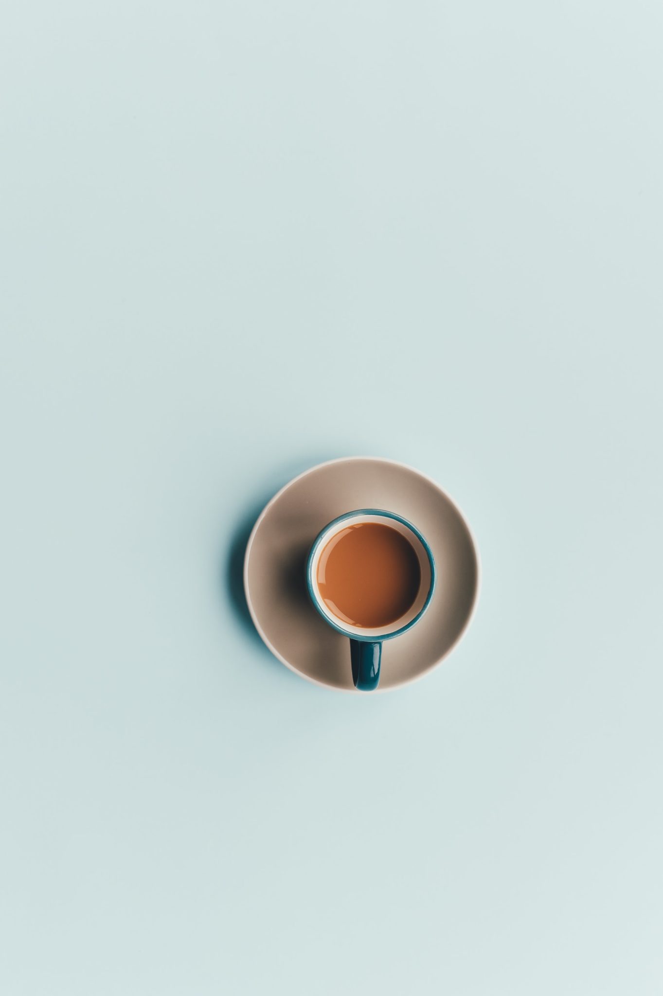 coffee in a blue mug on a saucer with a light blue background