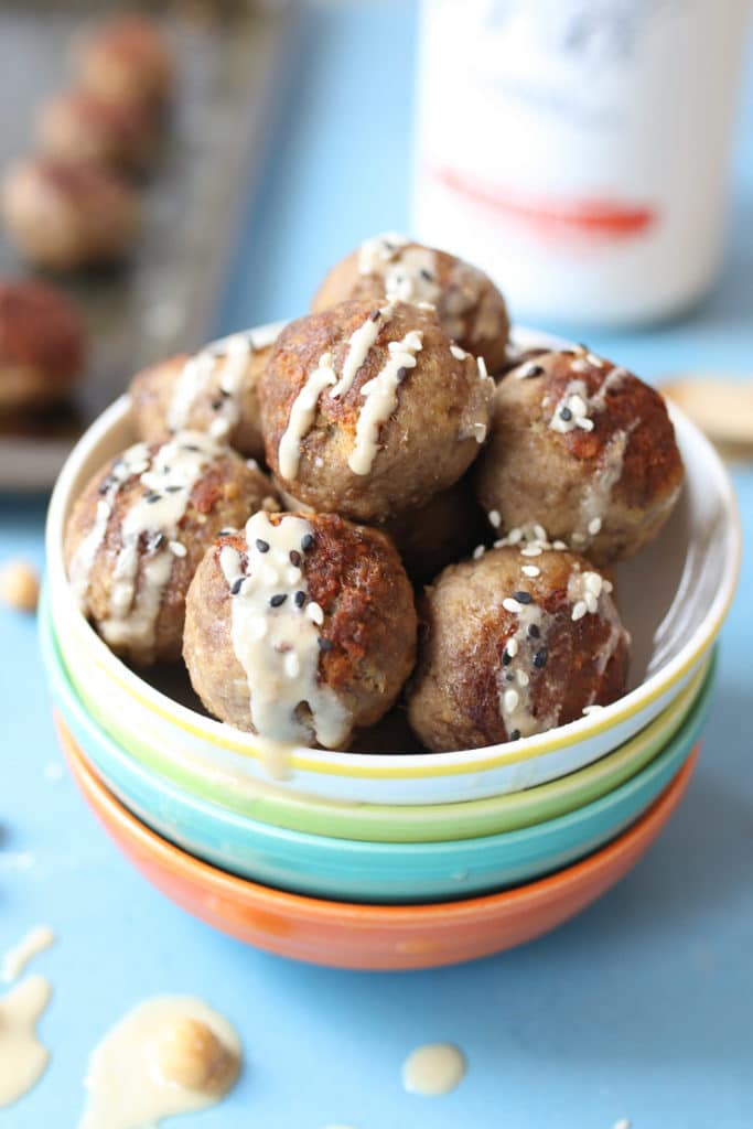 hummus meatballs in stacked colourful bowls drizzled with hummus 