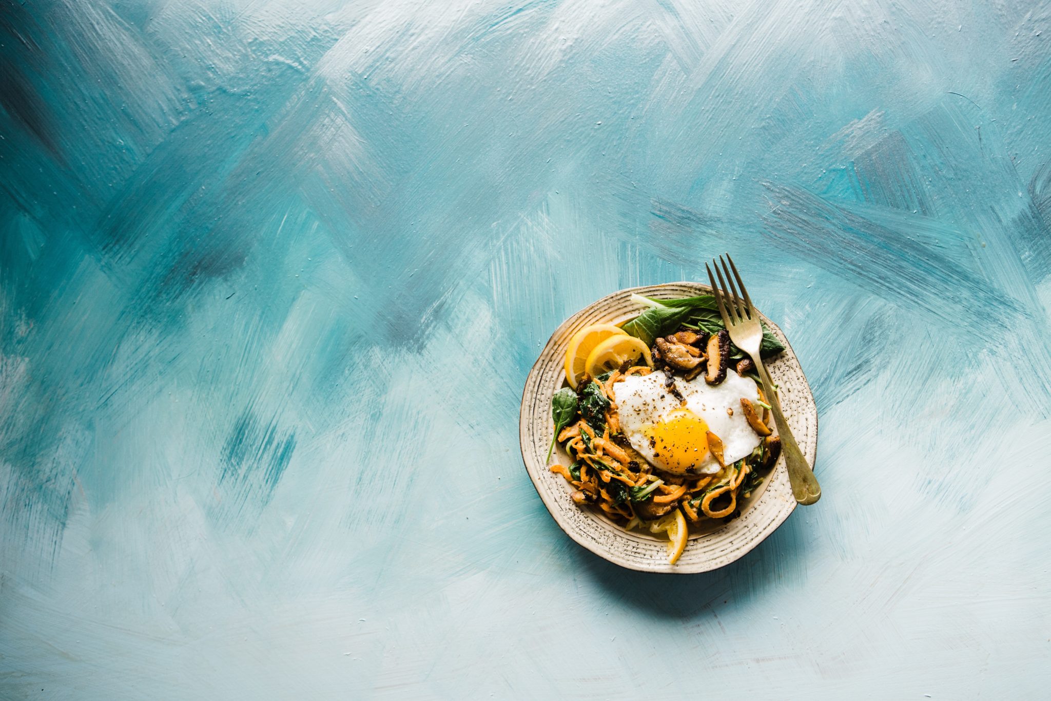 birds eye view of a take out meal served on a white dish with a silver spoon against a white and blue background