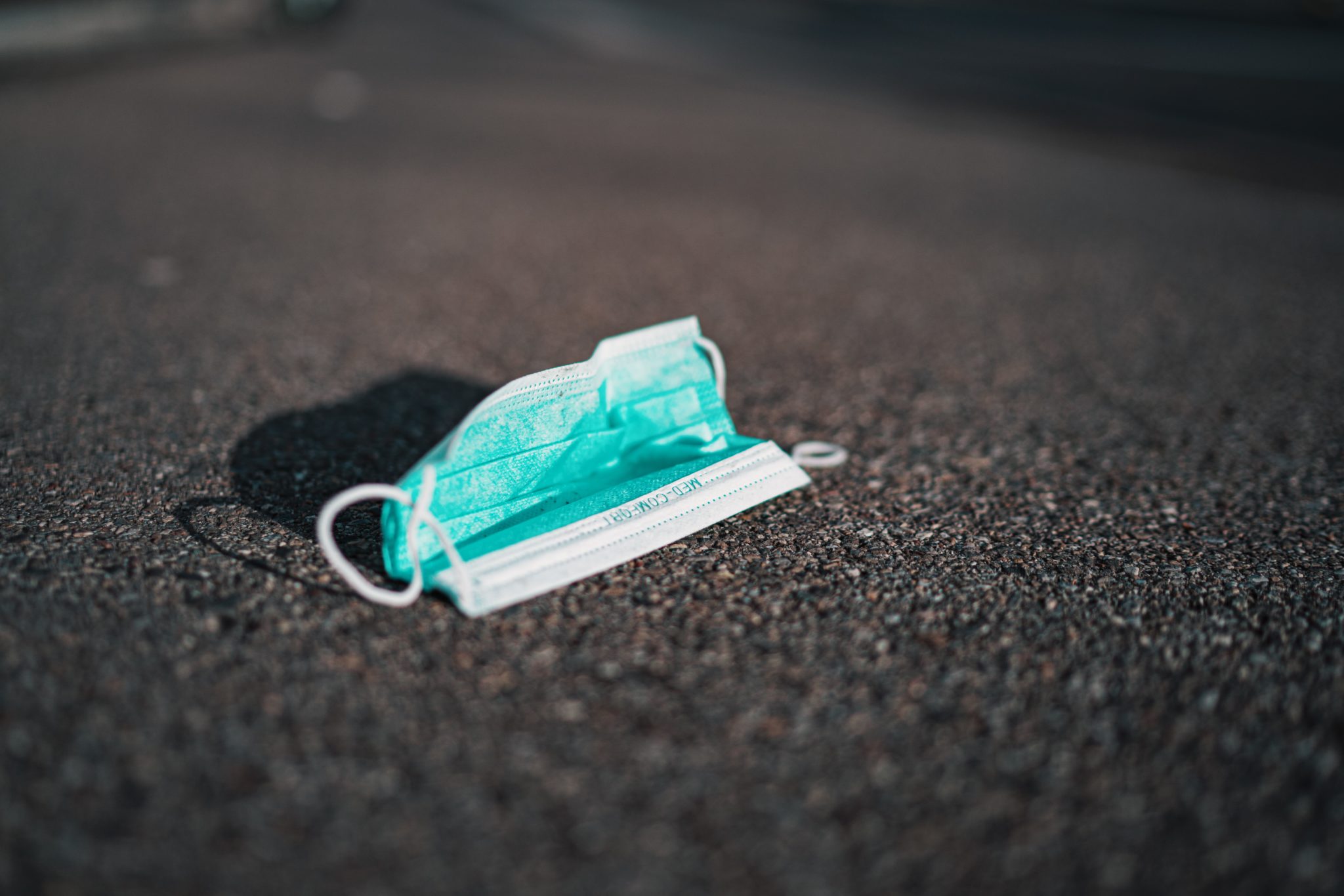 image of a blue surgical mask for coronavirus lying on the ground