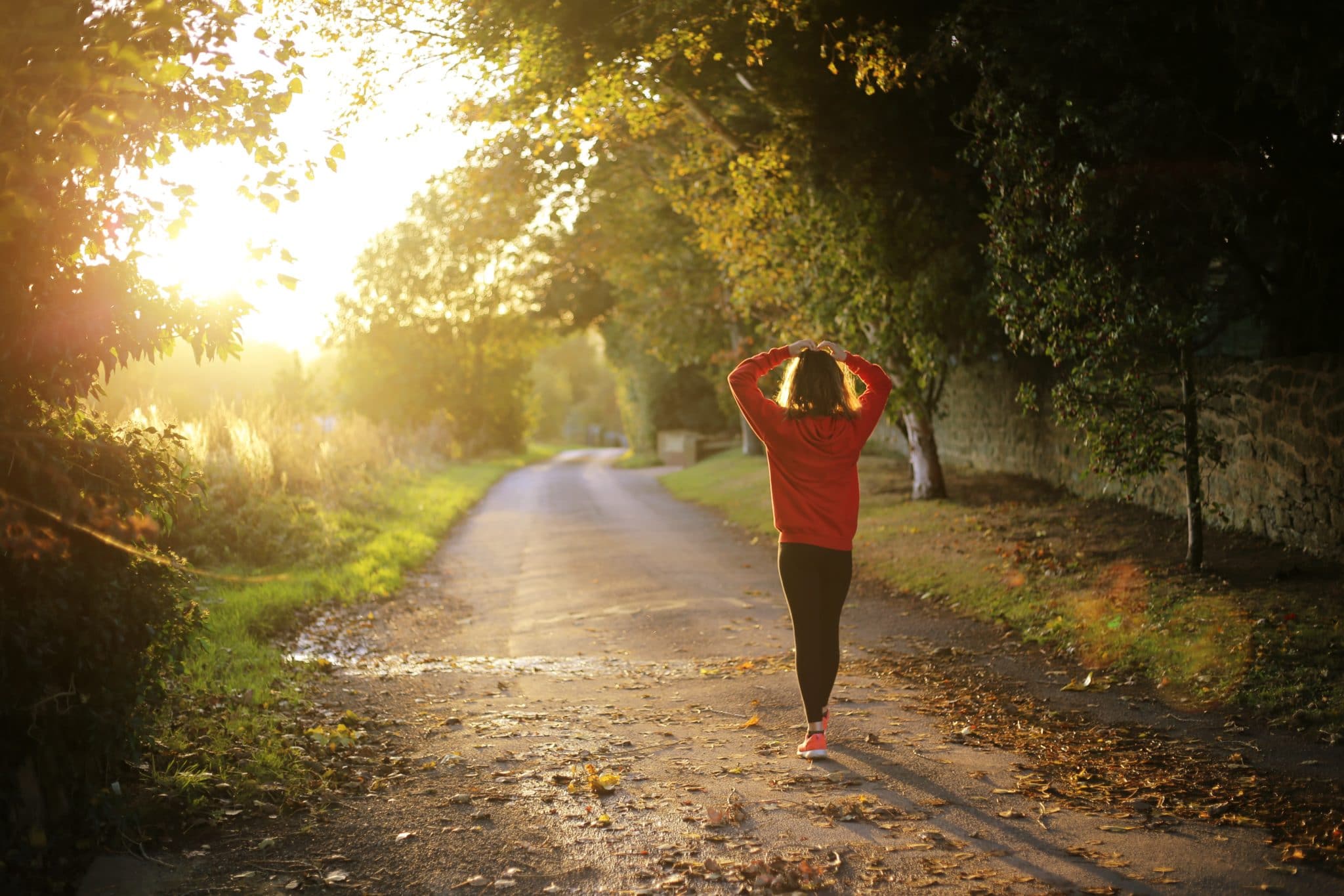 woman in orange sweatshirt walking in nature 