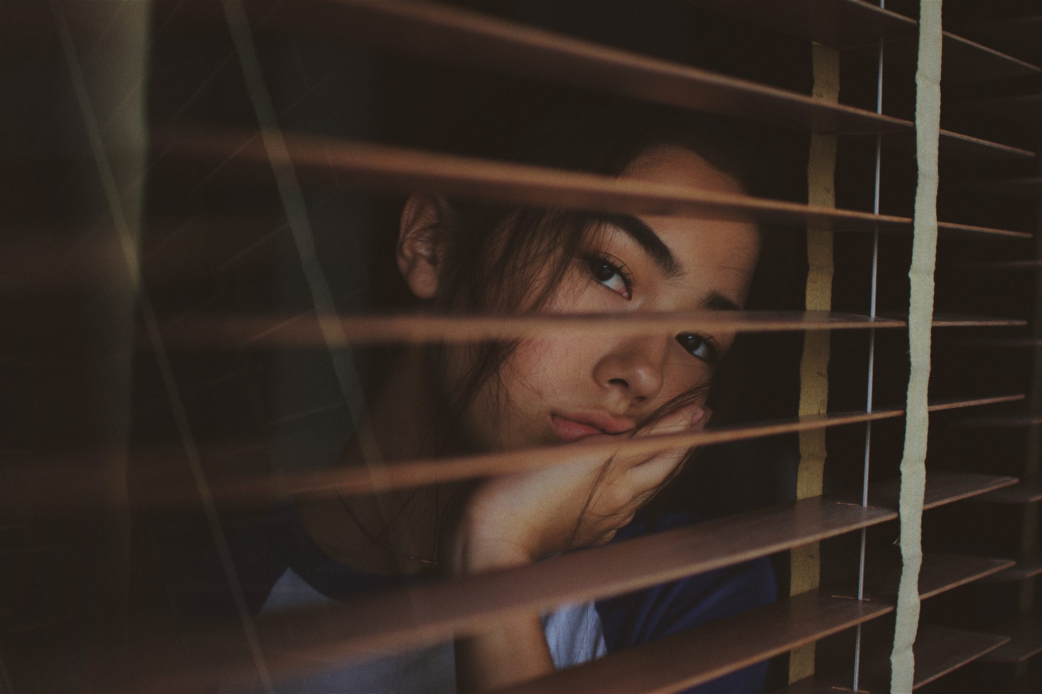 woman looking out the window during coronavirus isolation 