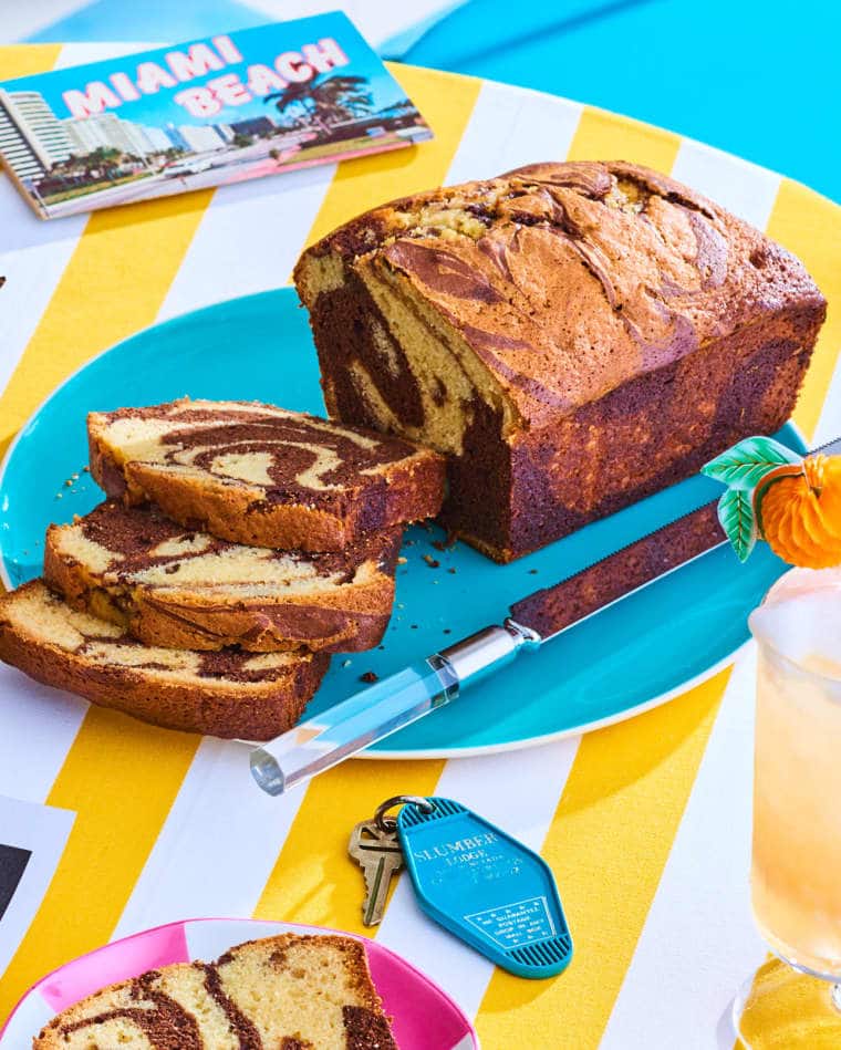 full shot of chocolate marble cake on a blue plate sitting on a yellow and white table