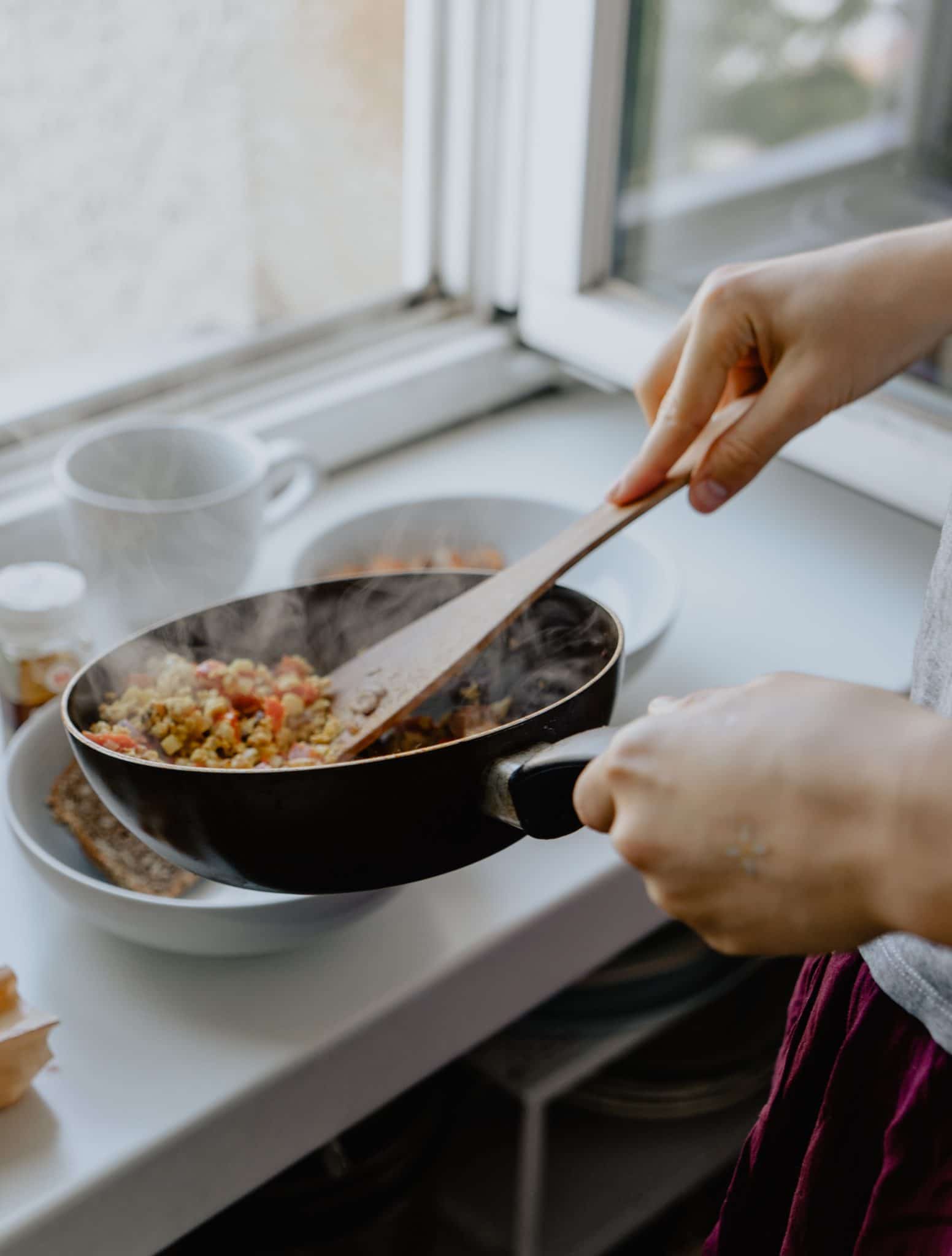 image of a home cooked meal being served into a white bowl from a black pan