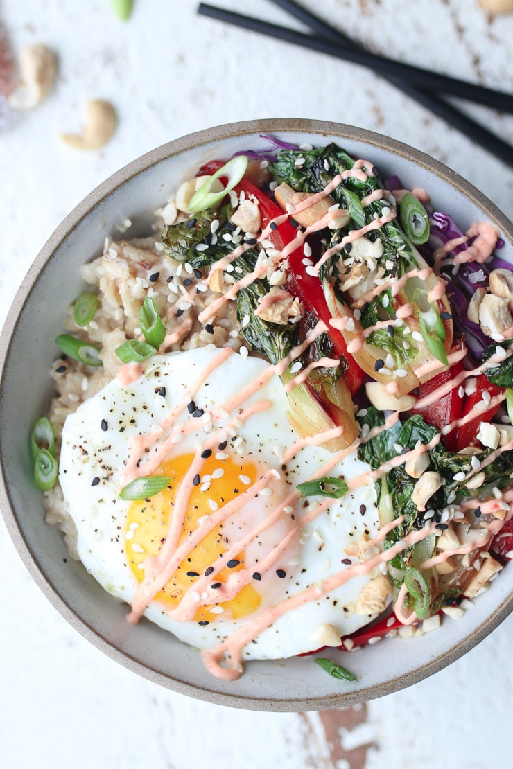 birds eye view of pantry staple savoury korean oatmeal bowl garnished with sesame seeds, spicy sauce, and green onions in a grey bowl