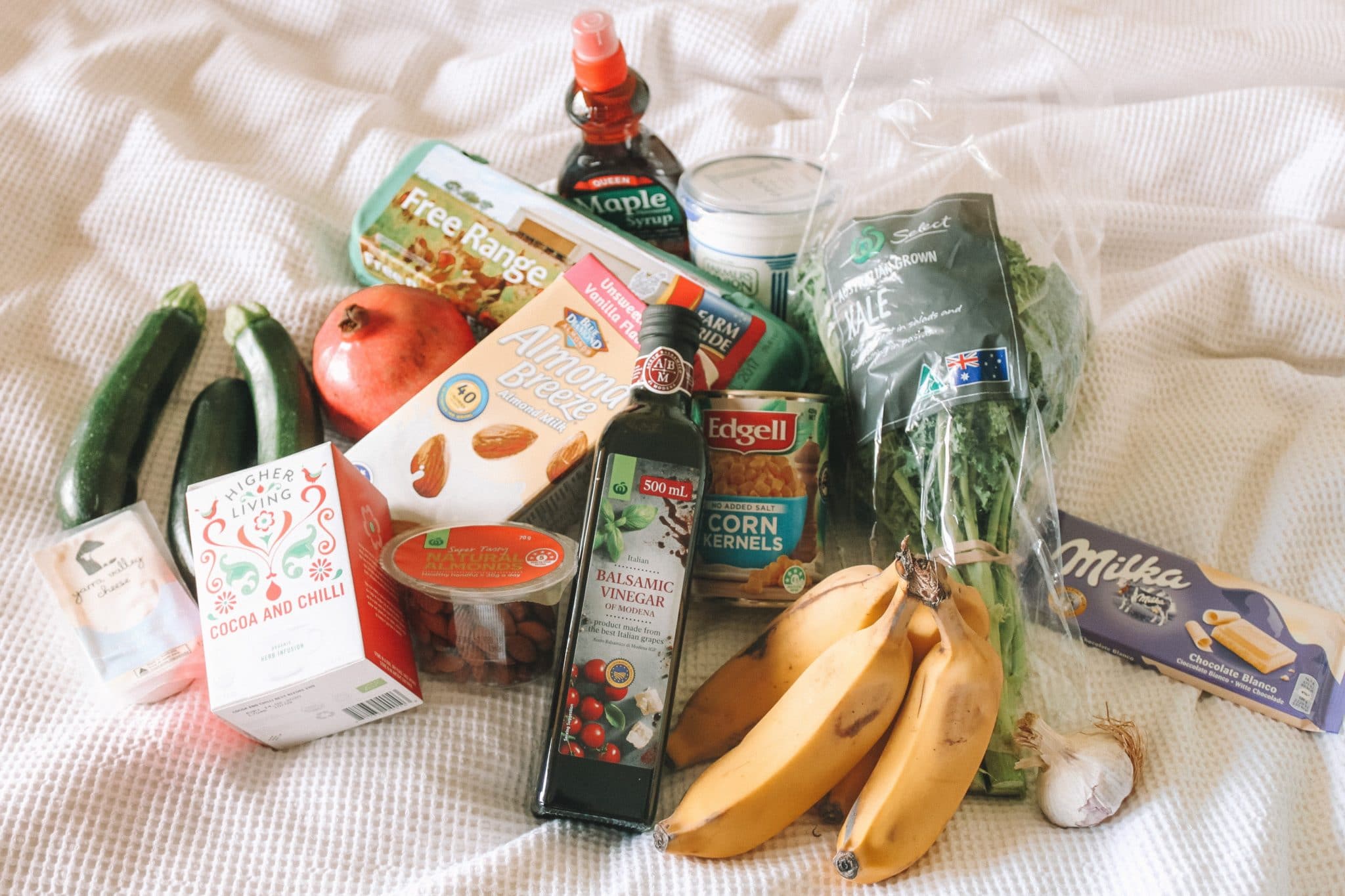 full shot image of multiple grocery items and pantry staples for social isolation against a white background 