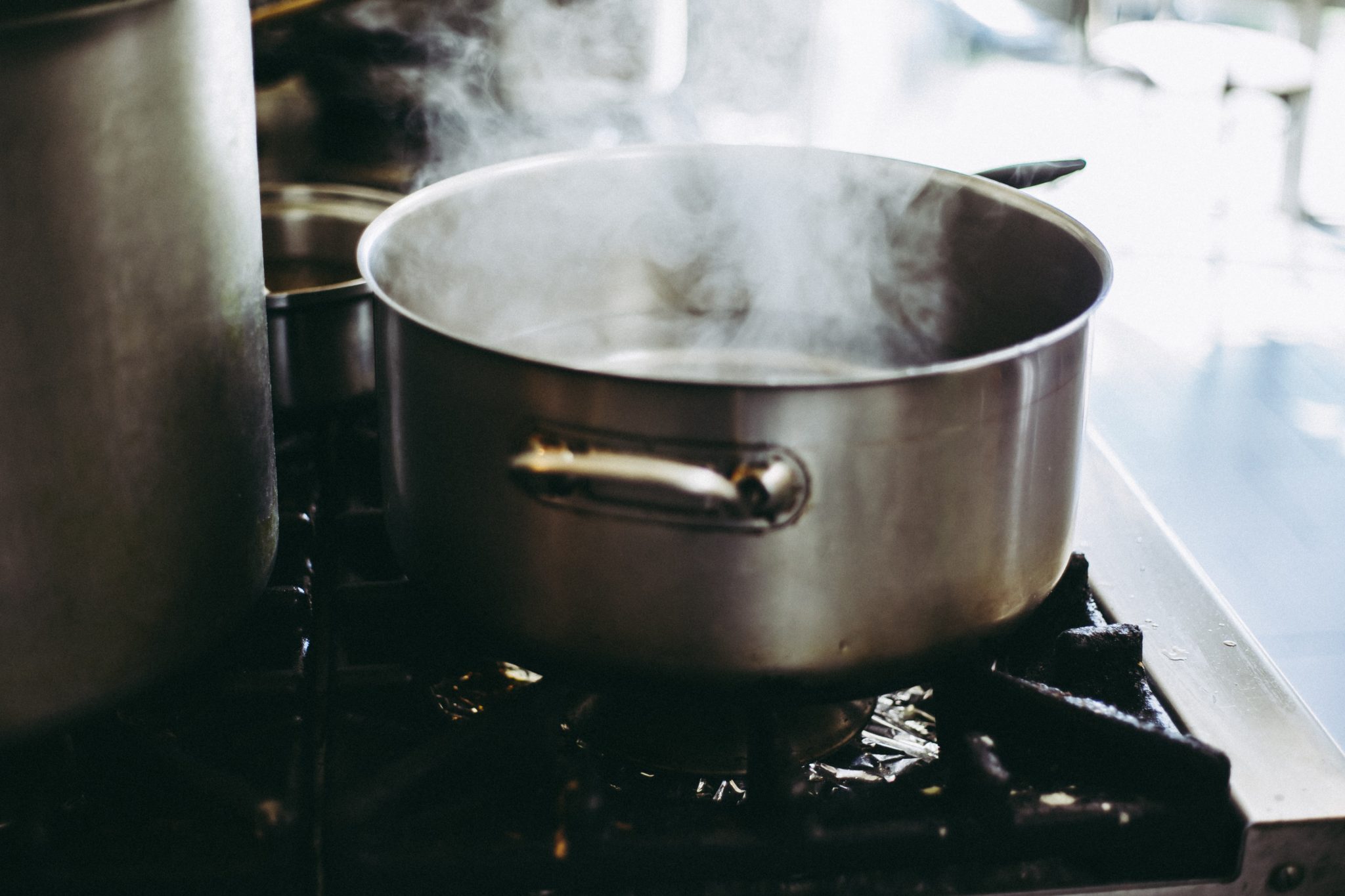 image of a large silver pot on a stove with steam coming out 