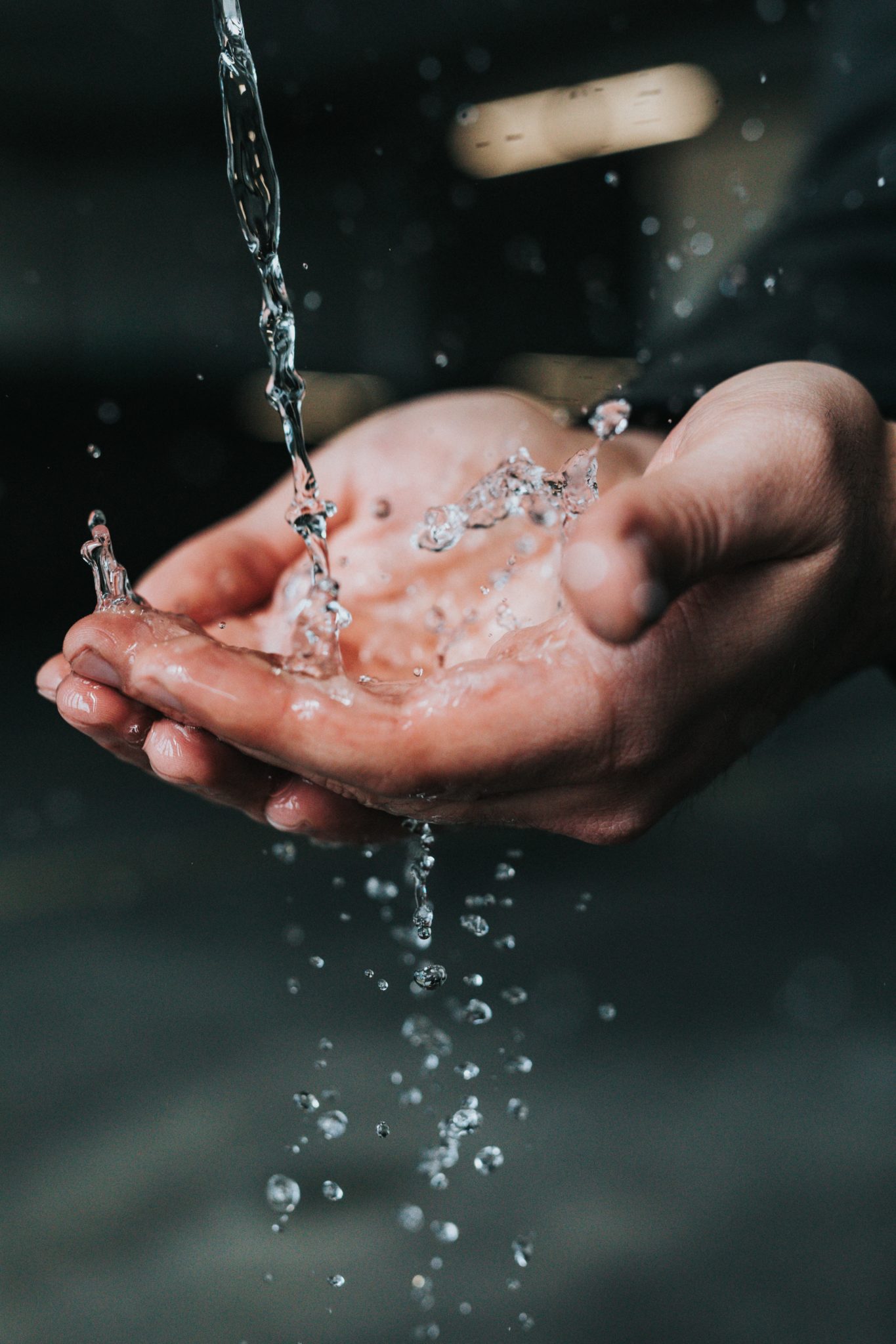 close up of person washing their hands for COVID-19 under water stream