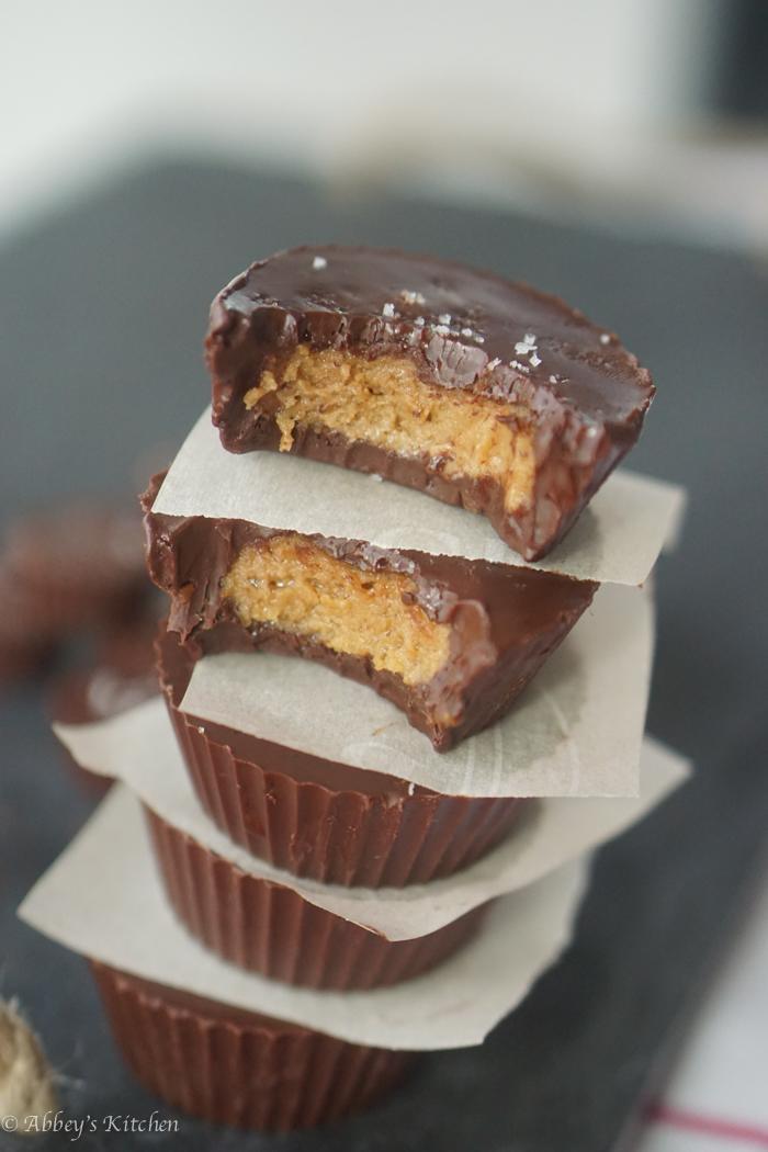 four pantry staple peanut butter cups stacked on top of one another garnished with sea salt with the first two bitten into