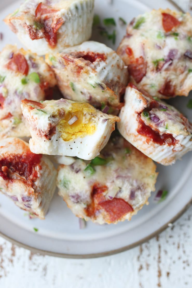 several pizza egg muffins stacked on a white plate 