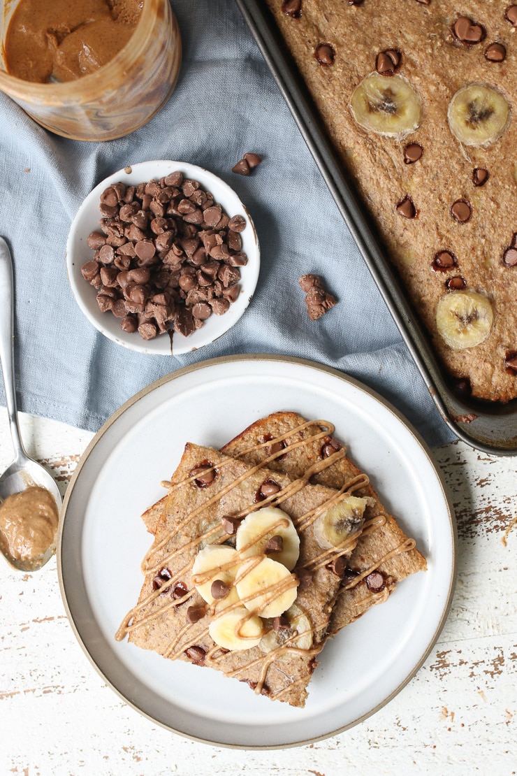 Birds eye view of protein sheet pan pancakes with chocolate chips, peanut butter and sheet pan in the background. 