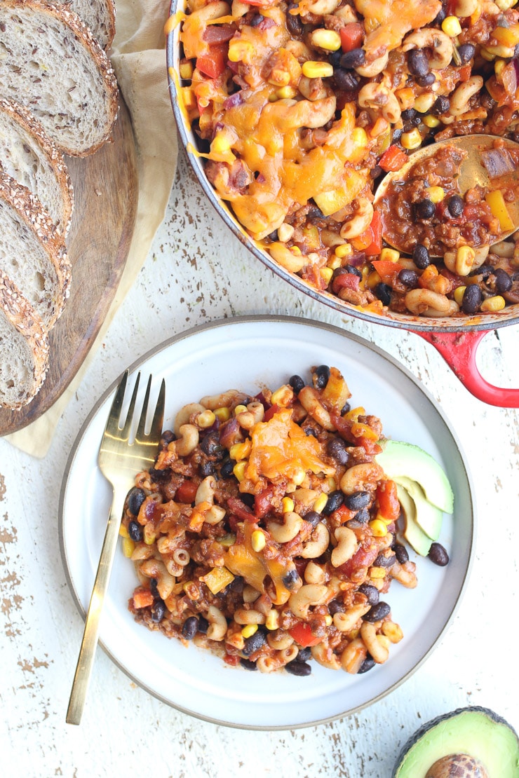 birds eye view of casserole on a white plate with a golden fork and remainder of casserole in a red pot in the background
