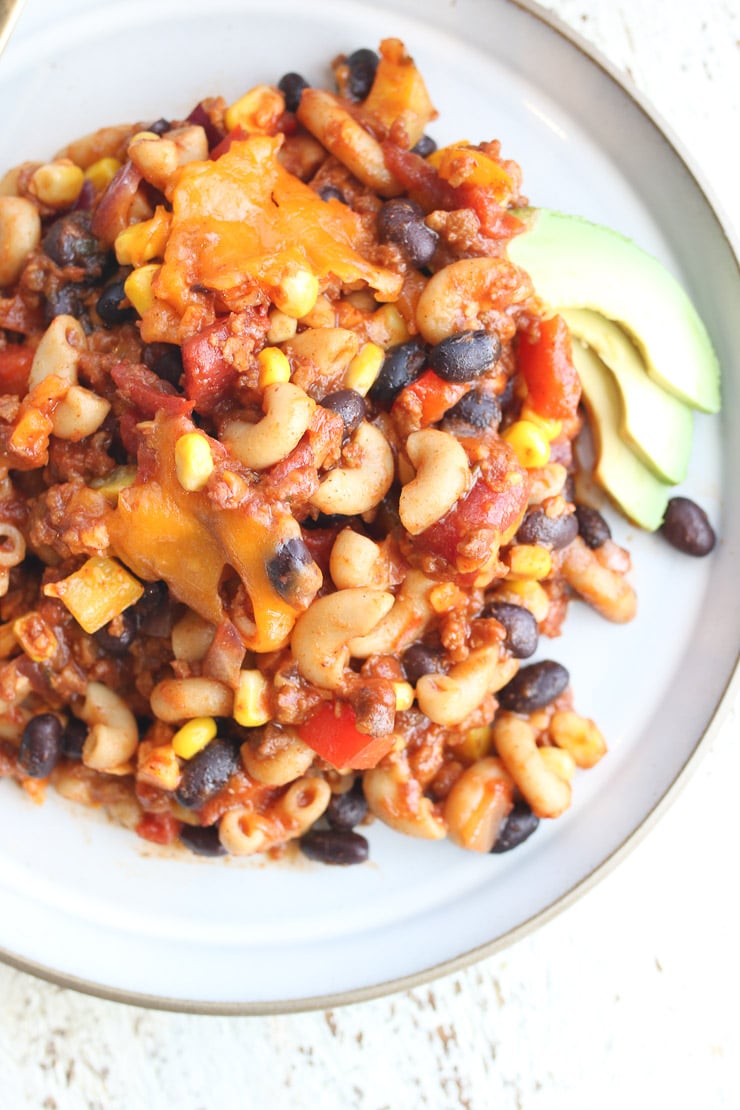 close up of vegan optional pantry staple taco casserole on a blue plate garnished with avocado slices on the side