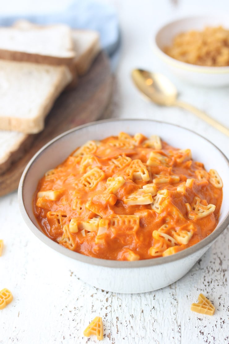 vegan alphagetti in a white bowl with bread and a gold spoon in the background