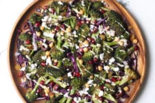 An overhead image of a wooden plate with gluten free vegan grilled broccoli, carrot and avocado salad with sesame dressing on it.