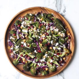 An overhead image of a wooden plate with gluten free vegan grilled broccoli, carrot and avocado salad with sesame dressing on it.