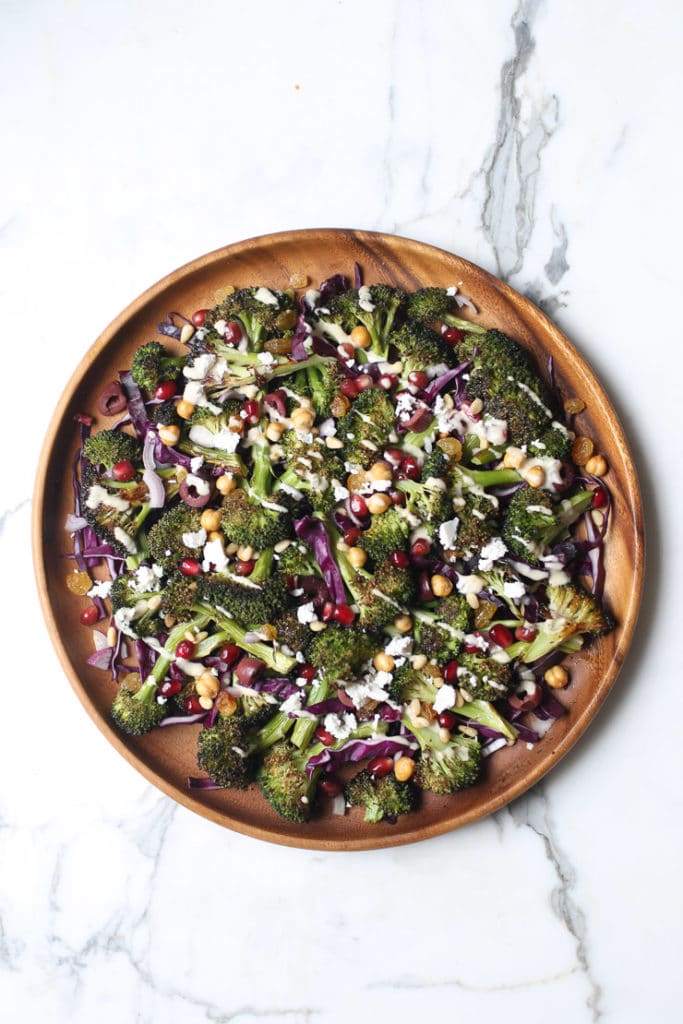 An overhead image of a wooden plate with gluten free vegan grilled broccoli, carrot and avocado salad with sesame dressing on it.