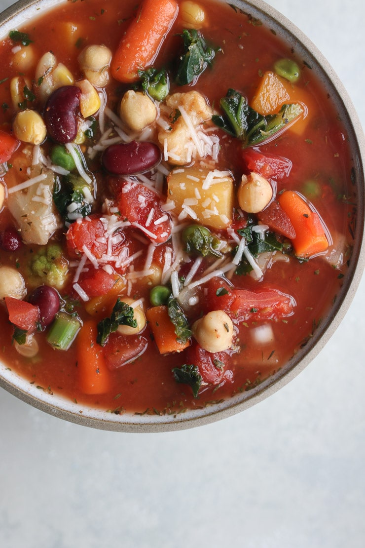 birds eye view of pantry bean & frozen vegetable soup topped with vegan cheese 