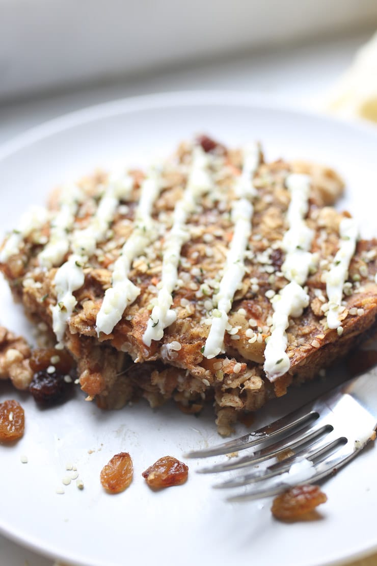 Carrot cake baked oatmeal on a white plate topped with raisins. 