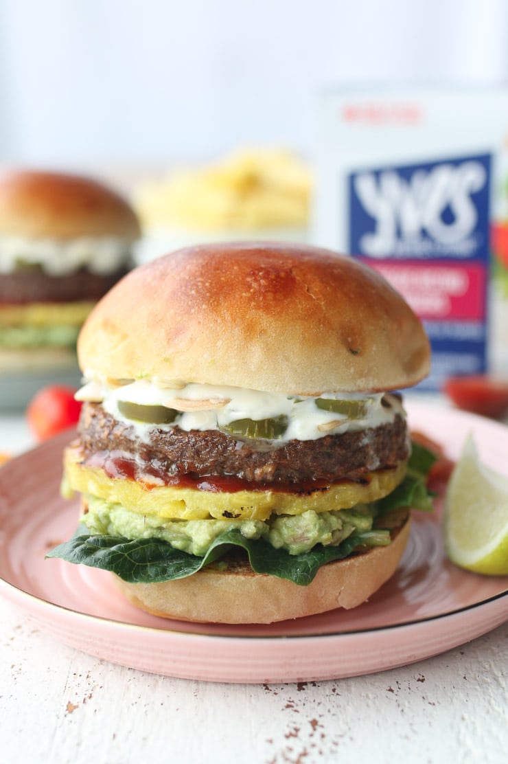 two vegetarian hawaiian spiced burgers vegarnished with lime aioli and fresh lime served on a red plate